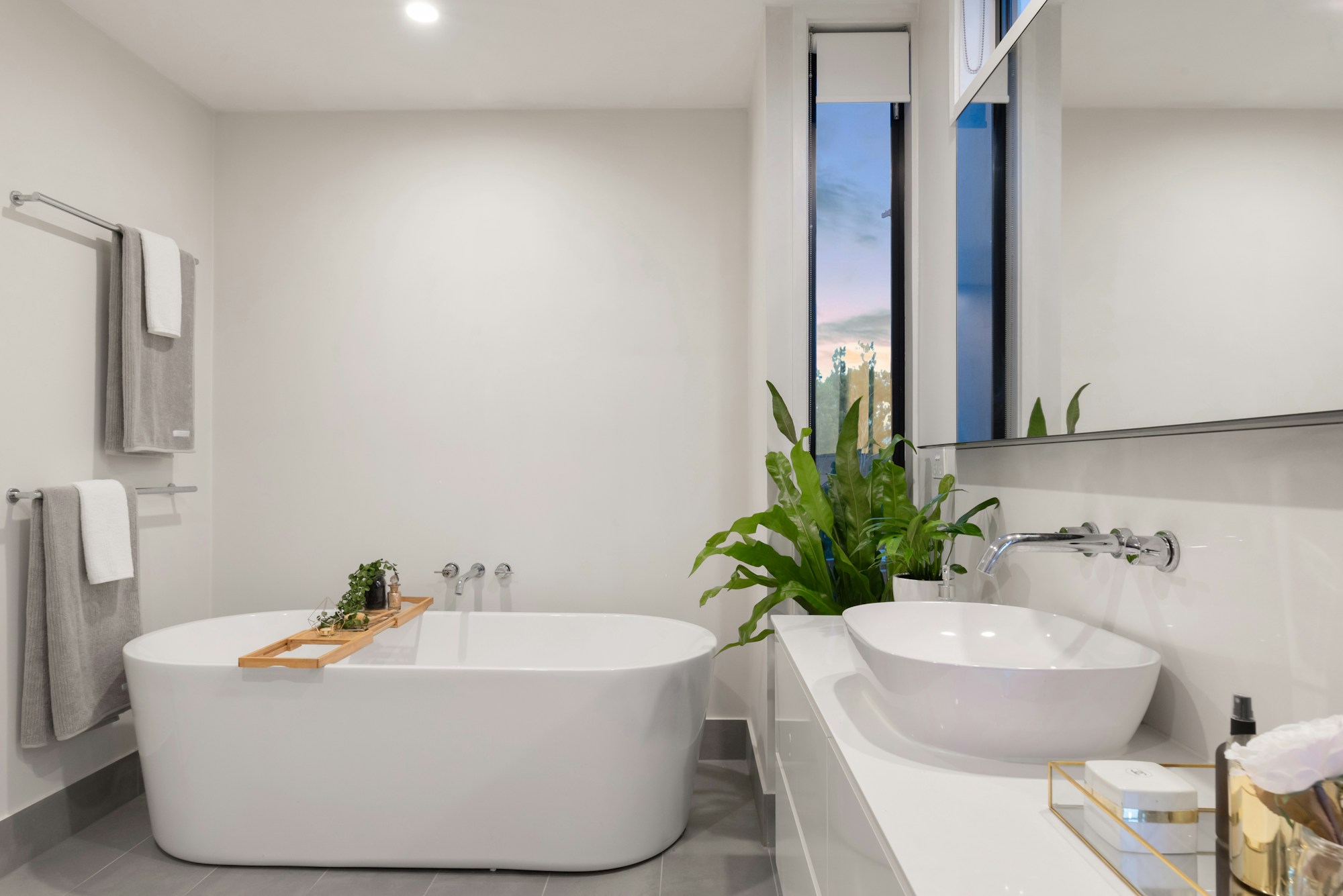 Sunlit bathroom with a freestanding bath, pale stone and sculptural white basins — interior reference